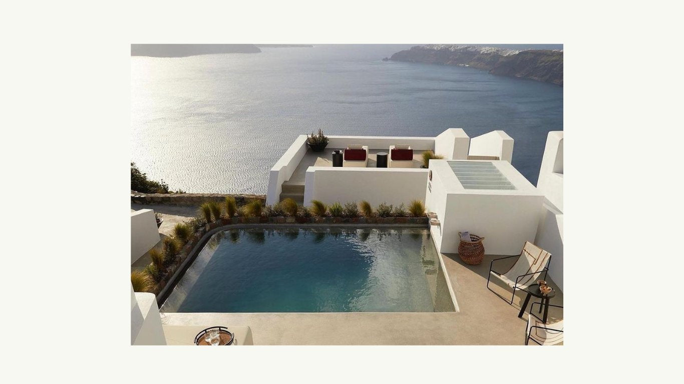 woman in a black linen jumpsuit standing by a pool looking out to the green valley.