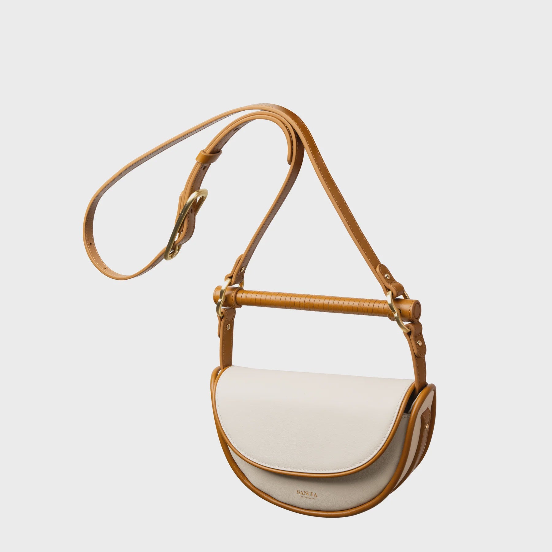 White handbag with tan leather strap on a light gray background